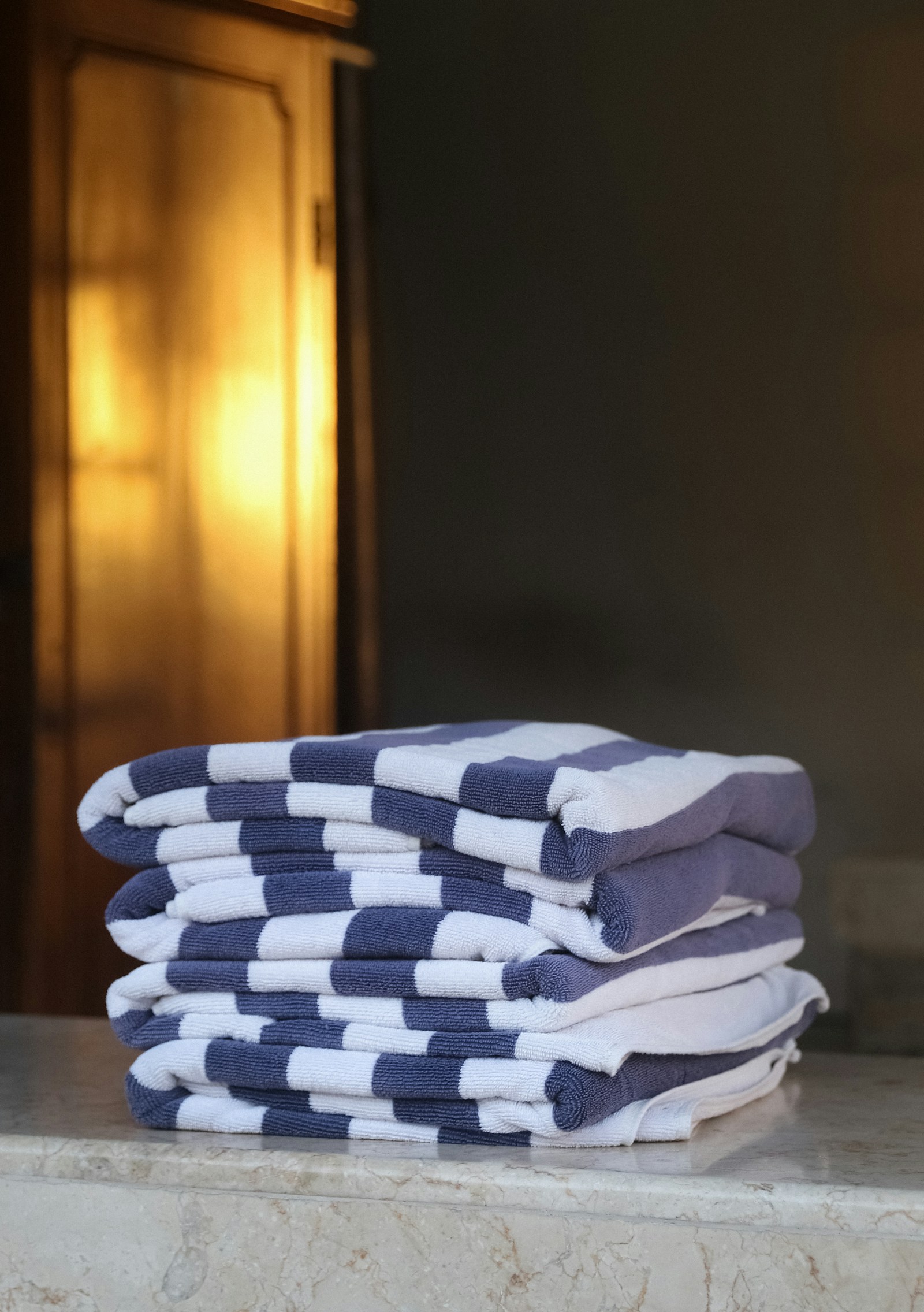 A stack of freshly laundered navy and white striped towels, folded and squared off
